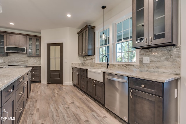 kitchen with decorative light fixtures, light hardwood / wood-style flooring, range hood, stainless steel dishwasher, and sink