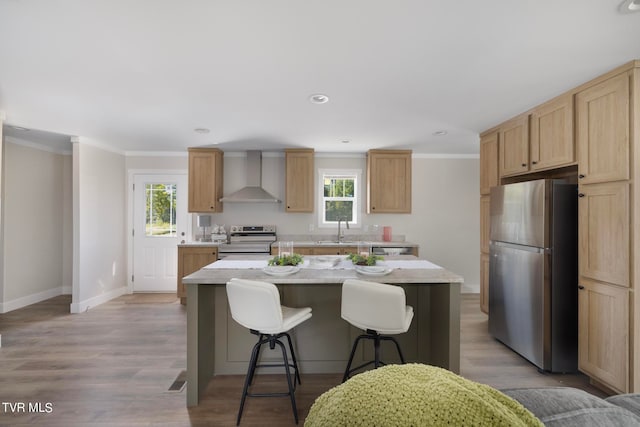 kitchen featuring a center island, light hardwood / wood-style flooring, stainless steel appliances, sink, and wall chimney exhaust hood