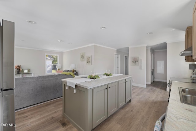 kitchen with light wood-type flooring, crown molding, exhaust hood, and a kitchen island