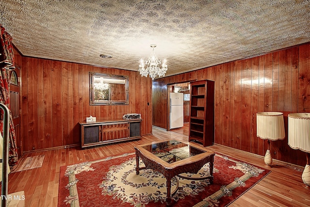 interior space featuring wooden walls, wood-type flooring, and a notable chandelier