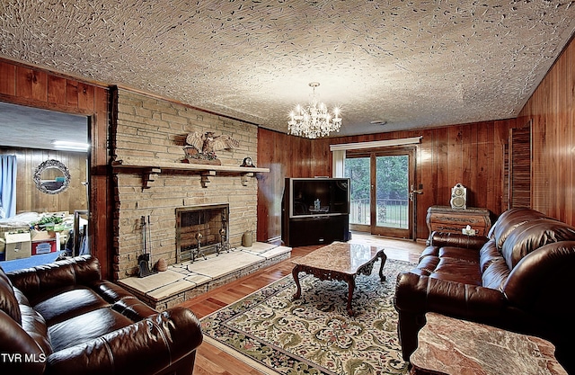 living room with wooden walls, a fireplace, a chandelier, and wood-type flooring