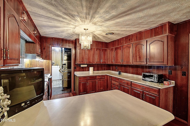 kitchen with washer / dryer, decorative light fixtures, an inviting chandelier, and wood walls