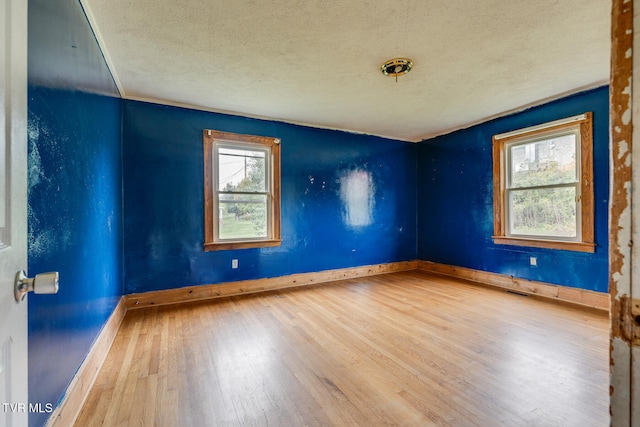 spare room with hardwood / wood-style flooring, a wealth of natural light, and a textured ceiling