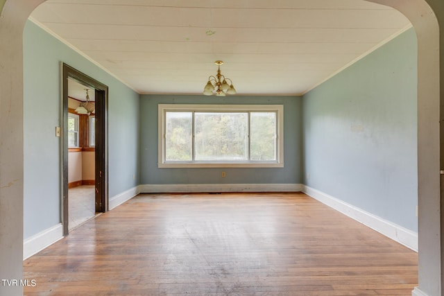 empty room with light wood-type flooring, crown molding, and a chandelier