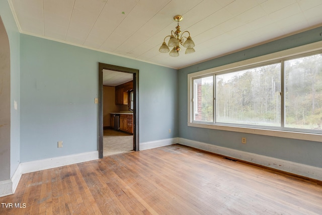 spare room featuring an inviting chandelier, crown molding, and light hardwood / wood-style flooring