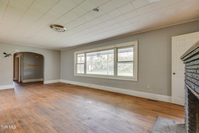 unfurnished living room featuring a stone fireplace, light wood-type flooring, and ornamental molding