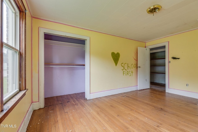 unfurnished bedroom with crown molding, a closet, and light hardwood / wood-style flooring