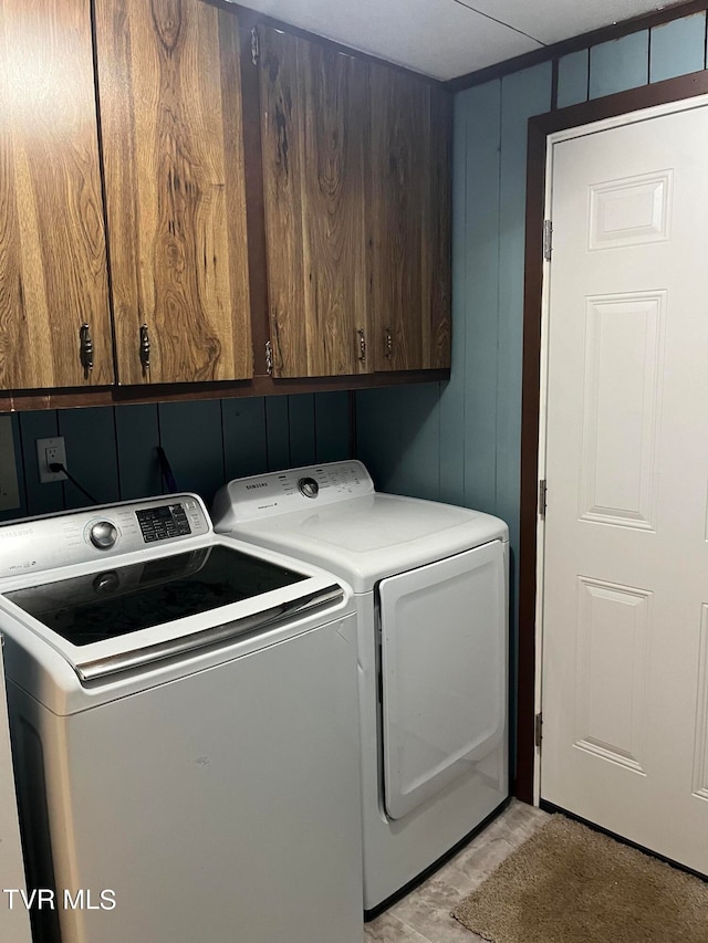 laundry room featuring cabinets, washer and clothes dryer, and light hardwood / wood-style floors