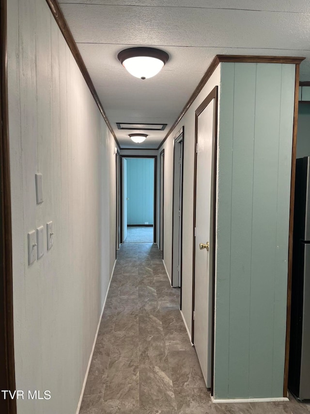 hall with wood walls and a textured ceiling