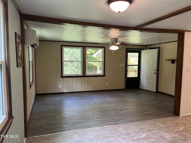 empty room featuring a wall mounted AC, hardwood / wood-style floors, ceiling fan, and wooden walls