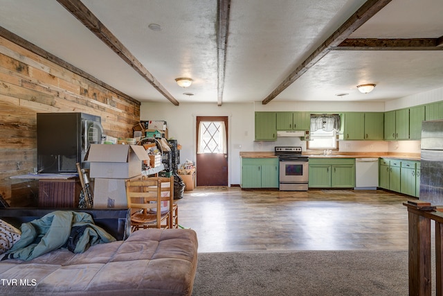 kitchen with beamed ceiling, wood walls, green cabinets, and appliances with stainless steel finishes