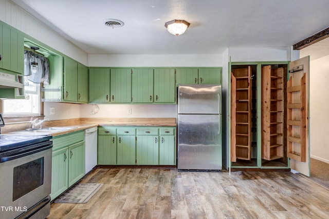 kitchen with green cabinetry, stainless steel appliances, and light wood-type flooring