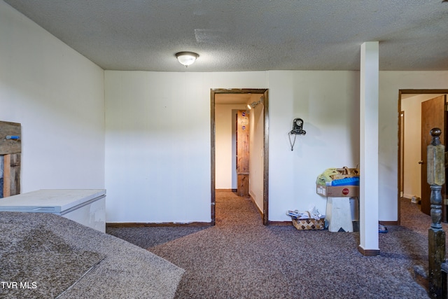 interior space featuring a textured ceiling and dark colored carpet