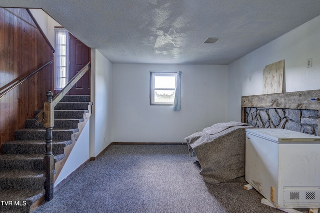 interior space with a textured ceiling, carpet flooring, and white fridge