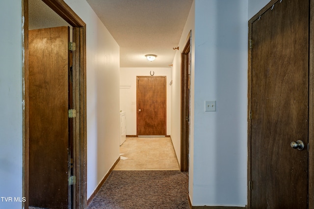 hall featuring a textured ceiling and light colored carpet