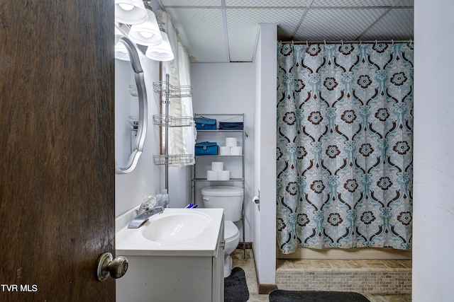 bathroom featuring vanity, a drop ceiling, and toilet