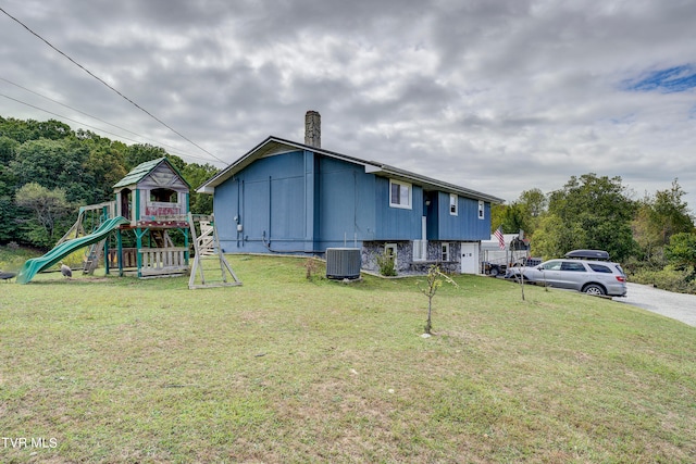 view of property exterior with a playground, a yard, and central AC unit