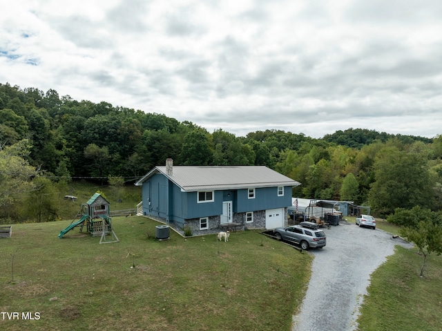 split foyer home with a playground, a garage, central AC unit, and a front yard