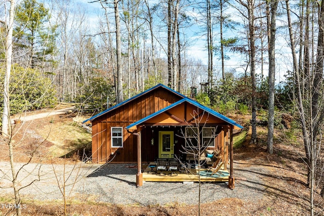 view of front facade featuring a deck, board and batten siding, and a view of trees