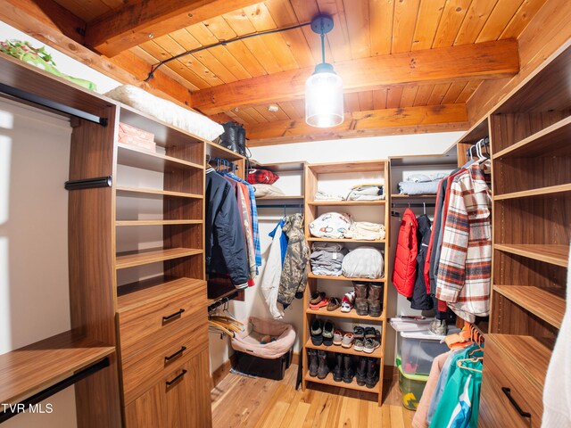 walk in closet with beamed ceiling and light hardwood / wood-style flooring