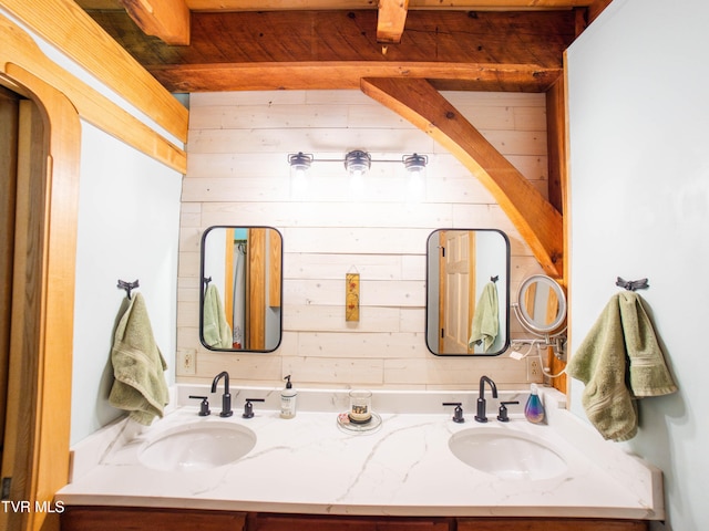 bathroom featuring wood walls, vanity, and beamed ceiling