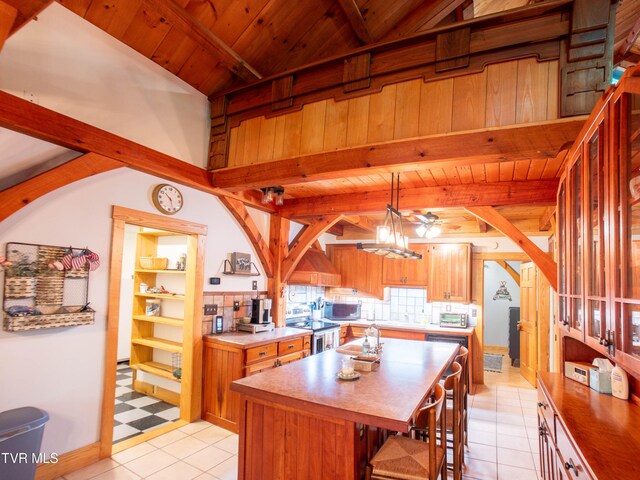 kitchen featuring pendant lighting, light tile patterned floors, appliances with stainless steel finishes, a center island, and decorative backsplash