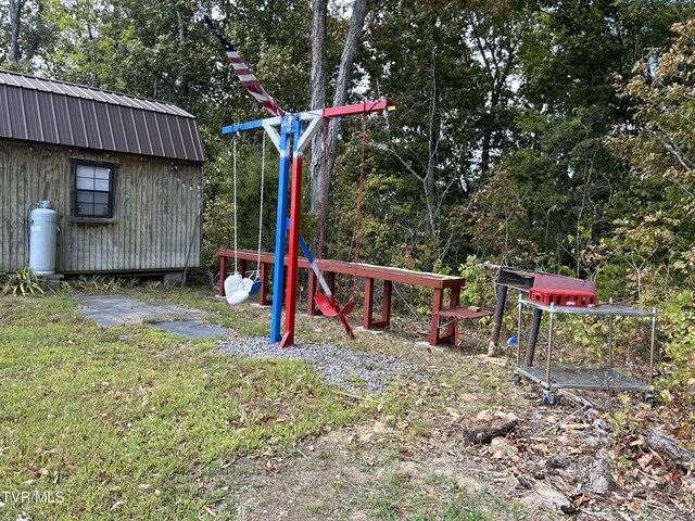 view of play area with a lawn and a storage shed