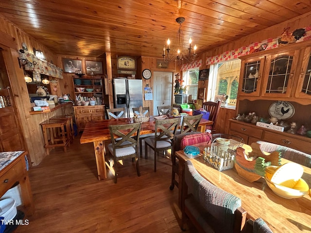 dining area featuring an inviting chandelier, wooden walls, wood-type flooring, and wood ceiling