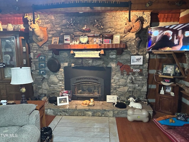 living room featuring a wood stove, hardwood / wood-style flooring, and beam ceiling