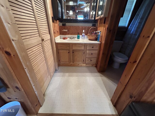 bathroom featuring toilet, backsplash, and vanity