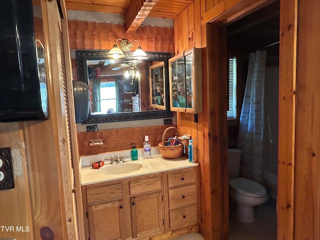 bathroom with wood walls, beam ceiling, toilet, and vanity