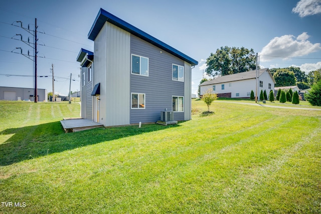 rear view of property featuring a lawn and central AC unit