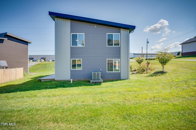 back of property featuring a lawn and central AC