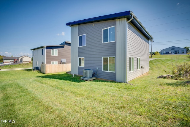 rear view of house featuring a lawn and cooling unit