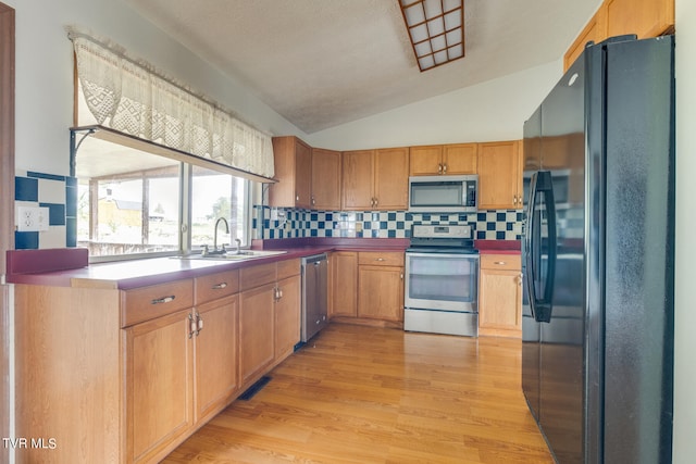 kitchen with sink, lofted ceiling, light hardwood / wood-style flooring, stainless steel appliances, and backsplash