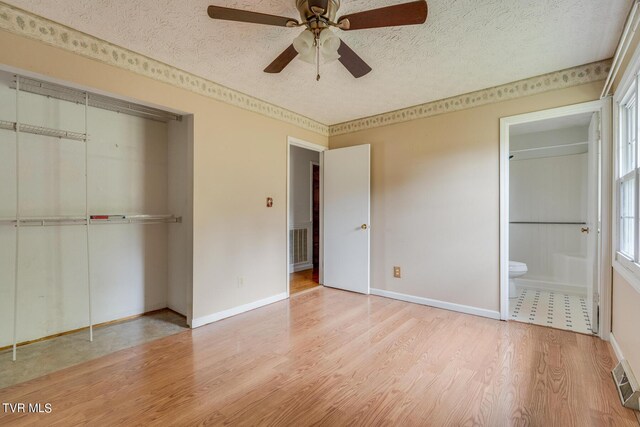 unfurnished bedroom featuring ceiling fan, a textured ceiling, light hardwood / wood-style flooring, a closet, and ensuite bathroom