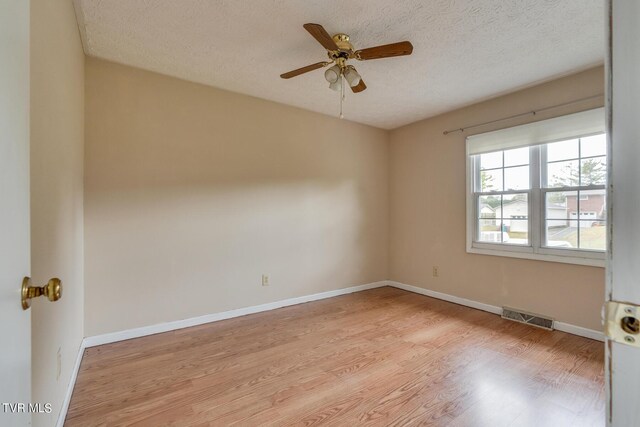 empty room featuring light hardwood / wood-style floors, ceiling fan, and a textured ceiling