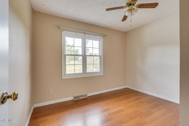 unfurnished room with ceiling fan, a textured ceiling, and light wood-type flooring