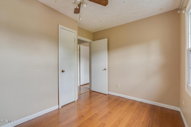 spare room featuring light hardwood / wood-style floors, ceiling fan, and a textured ceiling