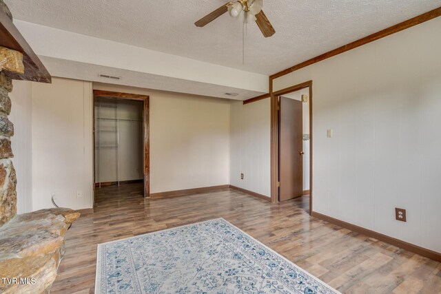 interior space featuring wood-type flooring, a textured ceiling, crown molding, and ceiling fan