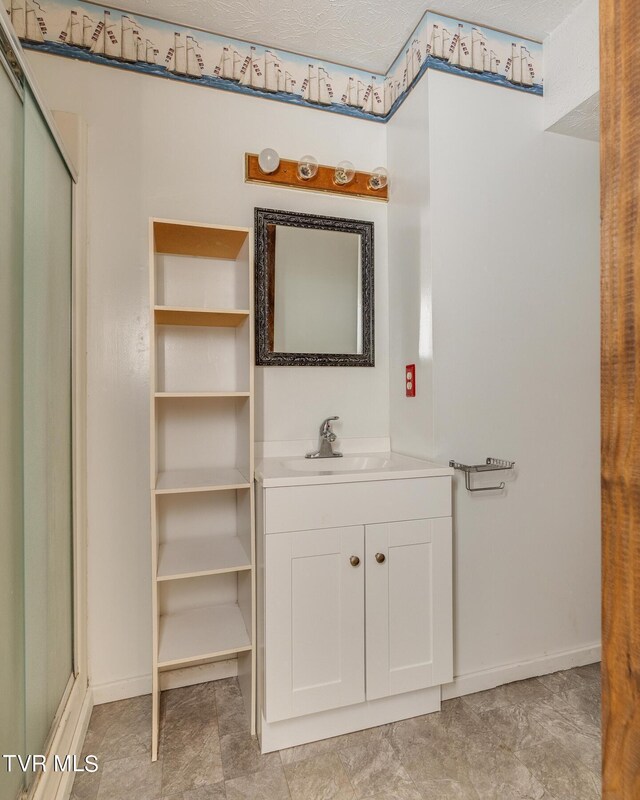 bathroom with a textured ceiling, a shower with door, and vanity