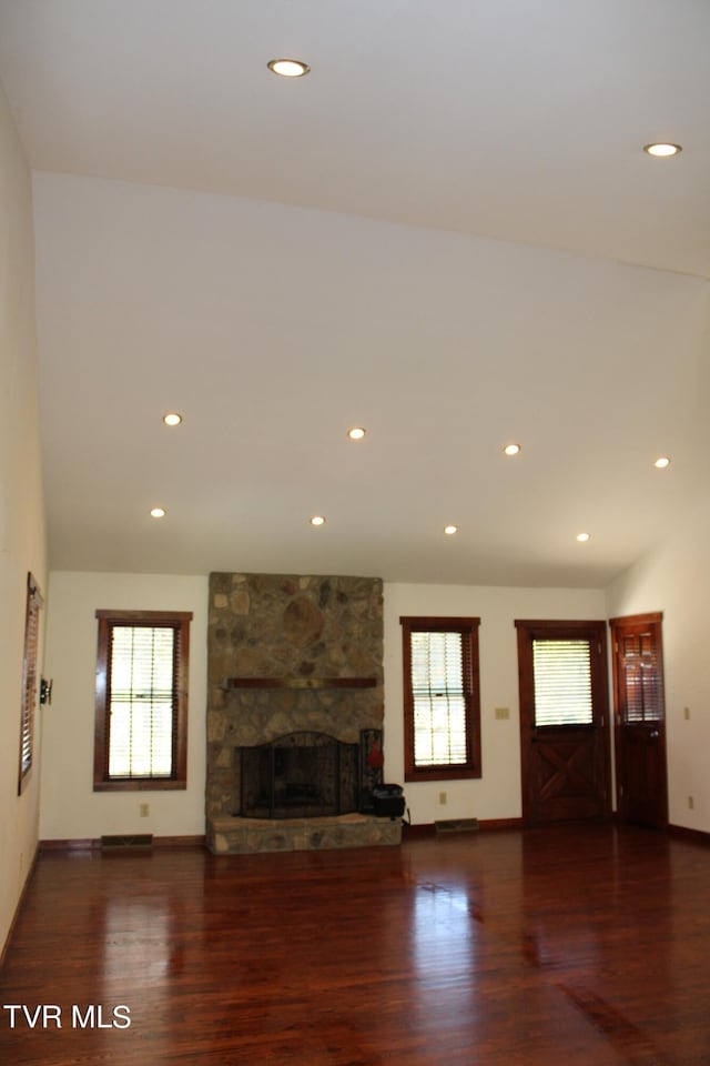 unfurnished living room with dark hardwood / wood-style floors, lofted ceiling, and a fireplace