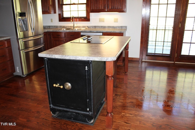 kitchen with stainless steel refrigerator with ice dispenser, black electric stovetop, sink, dark hardwood / wood-style floors, and a kitchen island