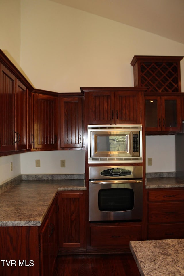 kitchen with dark hardwood / wood-style floors, vaulted ceiling, and appliances with stainless steel finishes