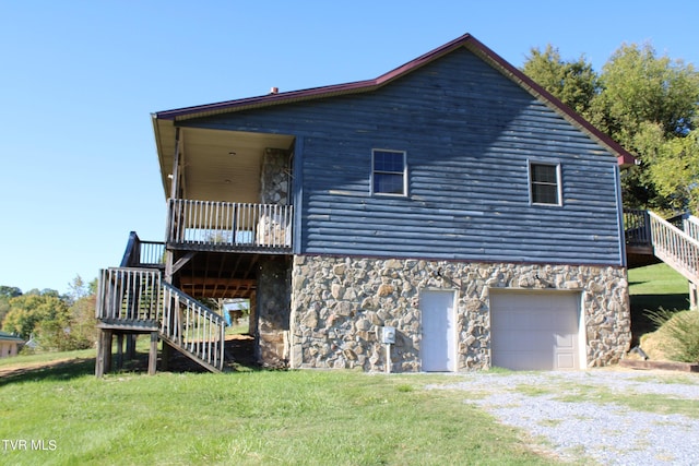 rear view of property featuring a garage, a yard, and a deck