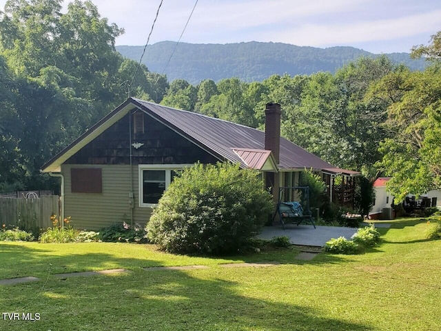 exterior space with a lawn, a mountain view, and a patio area