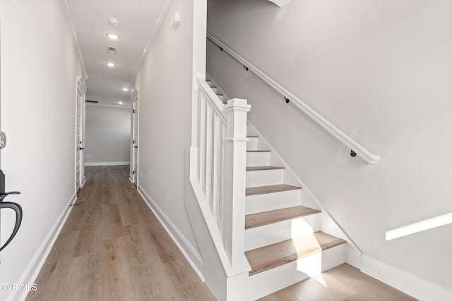 staircase featuring ornamental molding and hardwood / wood-style floors