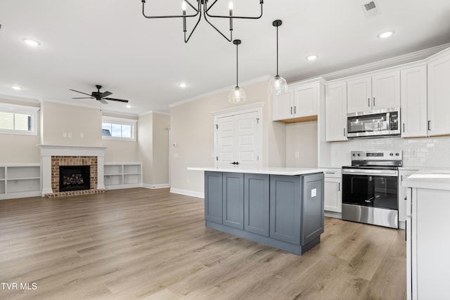 kitchen with appliances with stainless steel finishes, decorative light fixtures, a center island, and white cabinets