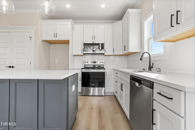 kitchen featuring appliances with stainless steel finishes, pendant lighting, gray cabinetry, white cabinets, and crown molding