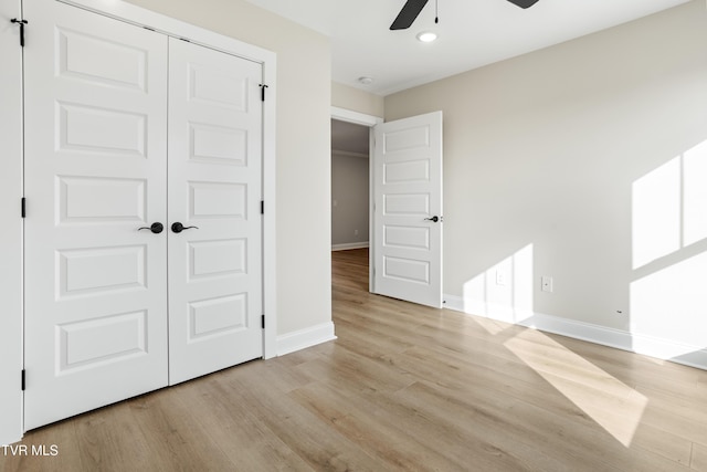 unfurnished bedroom featuring ceiling fan, a closet, and light wood-type flooring